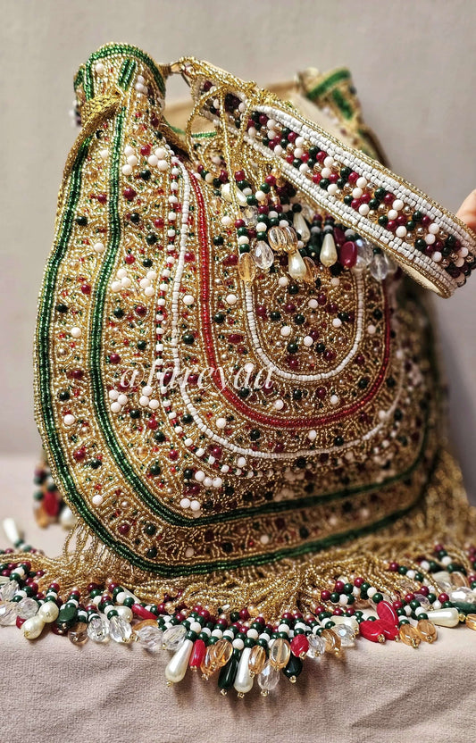 Handmade Qavali Potli in emerald with intricate beadwork and golden cutdana accents, featuring drawstring closure.